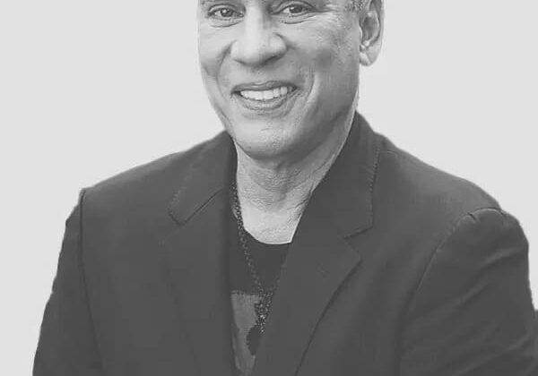 Smiling man in a suit, grayscale photo.