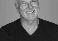 Smiling man in black shirt, grayscale image.