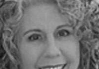 Smiling woman with curly hair, grayscale photo.