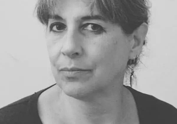 Woman with glasses, neutral expression, black and white.