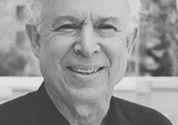 Older man smiling in black and white portrait.